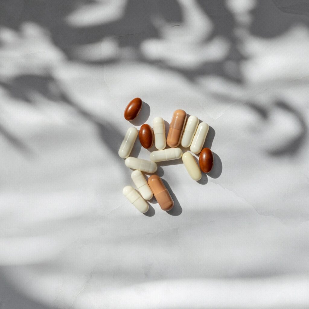 Medical treatment lifestyle concept. White and brown pills and capsules close up on white table background with natural sunlight shadow